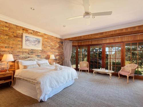 een slaapkamer met een groot bed en een bakstenen muur bij Netley Lodge for 10 Southern Highlands in Fitzroy