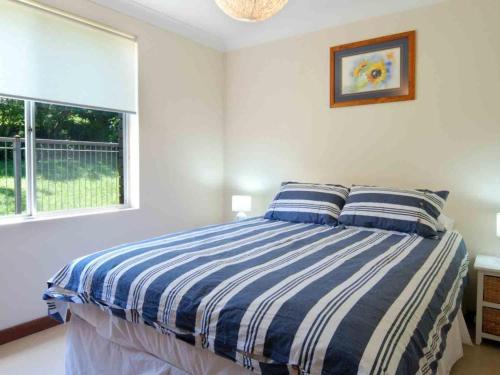 een slaapkamer met een bed met blauwe en witte strepen bij Pinkos Gerroa in Gerroa