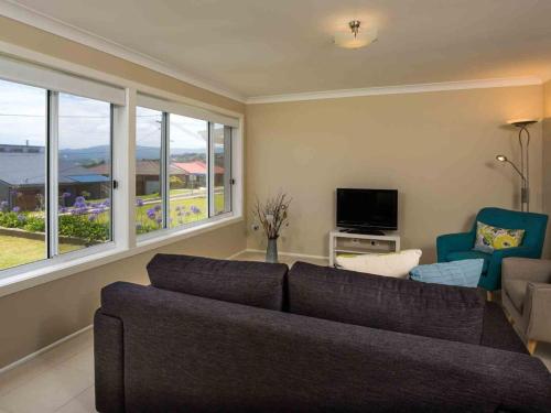 a living room with a couch and a tv and windows at Peninsula 180 Gerroa in Gerroa