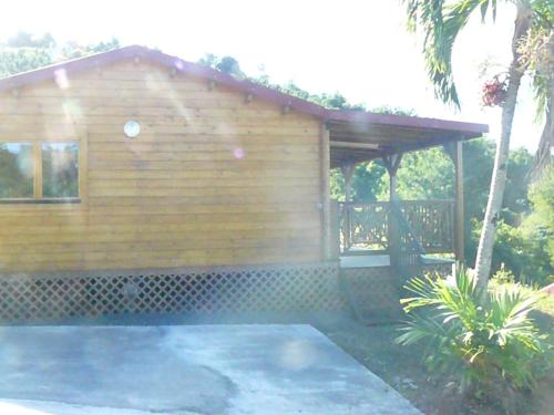 a small wooden cabin with a porch and a patio at les écolo-gîtes de l'Habitation Laurichesse in Vieux-Habitants