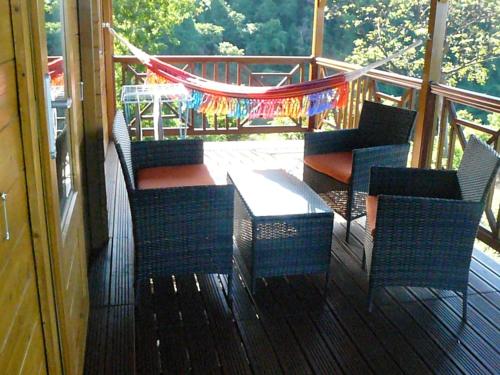 a porch with chairs and a table and a hammock at les écolo-gîtes de l'Habitation Laurichesse in Vieux-Habitants