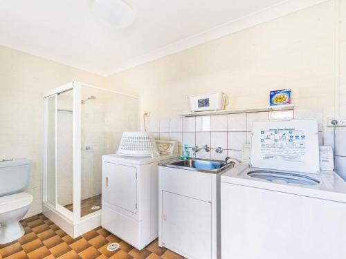 une petite salle de bains avec un lave-linge et un lavabo dans l'établissement Sandals at the Bay Upstairs sleeps 6 Hyams Beach, à Hyams Beach