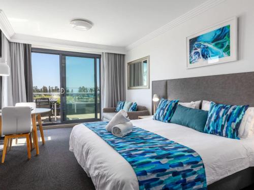 ein Hotelzimmer mit einem großen Bett und einem Tisch in der Unterkunft Sebel Harbourside 301 Kiama in Kiama