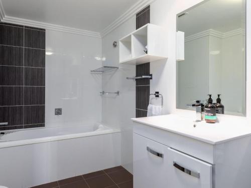 a bathroom with a sink and a tub and a mirror at Sebel Harbourside 301 Kiama in Kiama