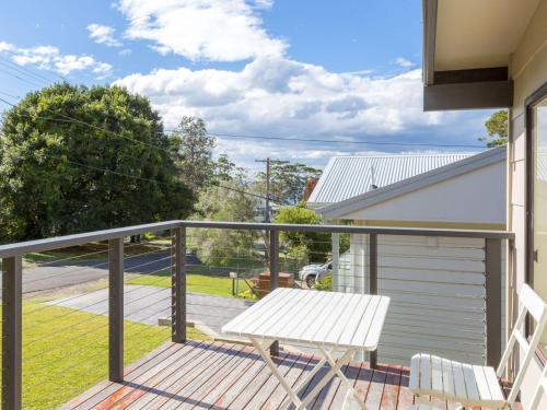 a deck with a white bench and a house at Shanti at Hyams Beach in Hyams Beach