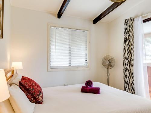 a bedroom with a white bed and a window at Shanti at Hyams Beach in Hyams Beach