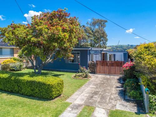a blue house with a tree in the yard at Spindrift Kiama in Kiama
