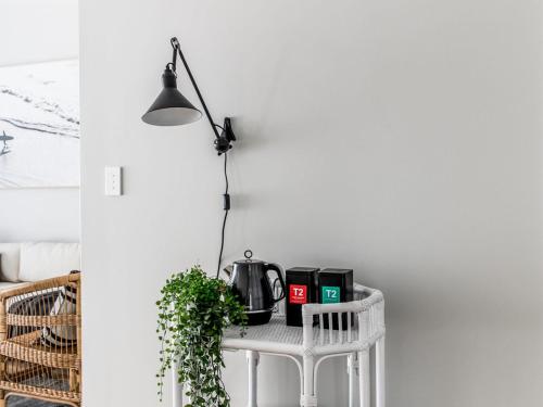 a white table with a lamp and a plant on it at The Condo Gerroa in Gerroa