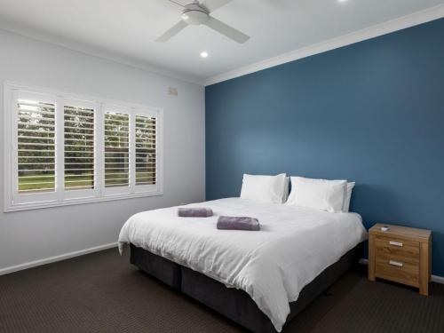 ein blaues Schlafzimmer mit einem großen Bett und einem Fenster in der Unterkunft The Pacific Werri Beach Gerringong in Gerringong