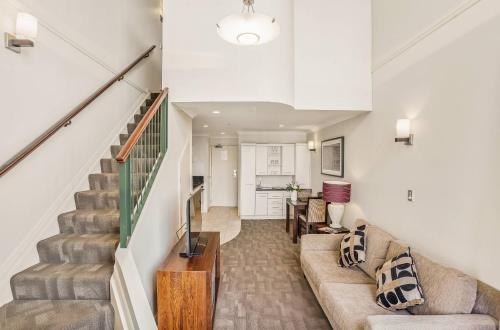 a living room with a couch and stairs at Parkside Hotel & Apartments in Auckland