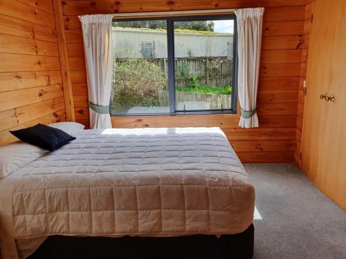 a bedroom with a large bed and a window at Aqua On The Beach in Auckland