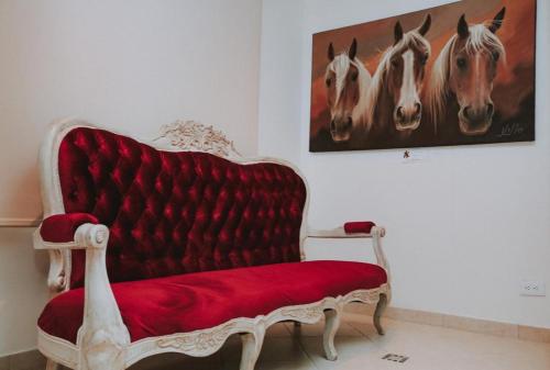 a red bench in a room with a painting of horses at HOTEL GRAND BOUTIQUE in Fusagasuga