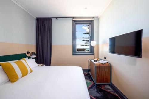 a hotel room with a bed and a flat screen tv at Stay at Hotel Steyne in Sydney