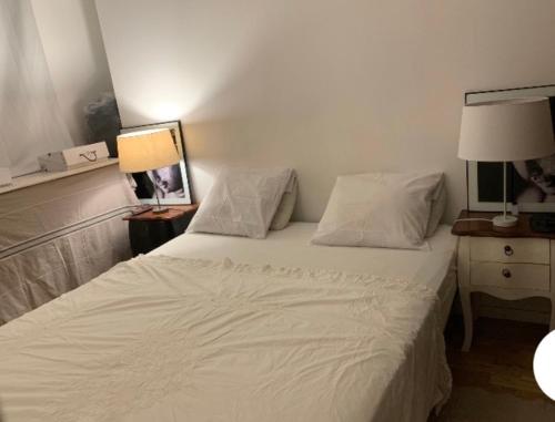 une chambre avec un lit avec des draps blancs et des oreillers dans l'établissement Agréable Logement à Vierzon centre, à Vierzon