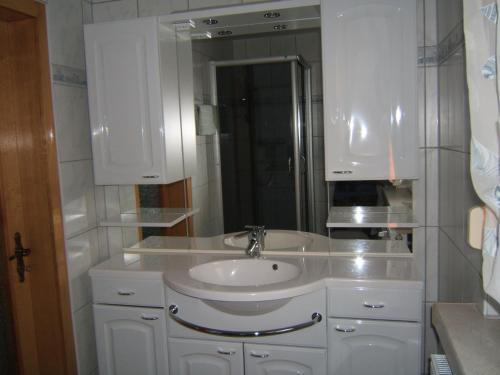 ein weißes Badezimmer mit einem Waschbecken und einem Spiegel in der Unterkunft Ferienwohnung Veit in Pennewitz