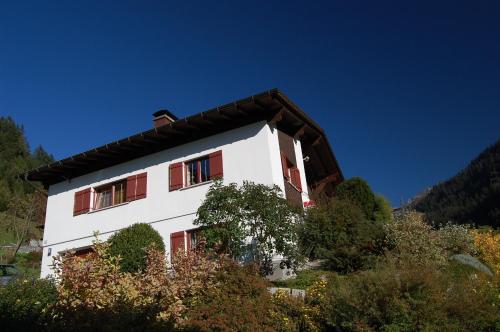 a white house with red windows on a mountain at Haus Kinsperger in Klösterle am Arlberg