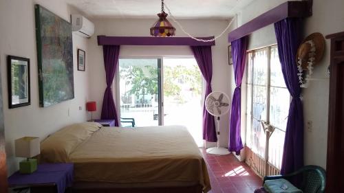 Schlafzimmer mit einem Bett mit lila Vorhängen und einem Fenster in der Unterkunft Casa Magua in Bucerías