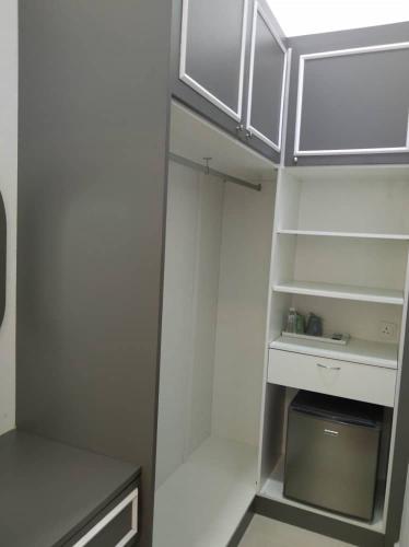 a small kitchen with white cabinets and a refrigerator at Captain's Cabin Resort - Naval Heritage (Swimming Pool) in Kota Bharu