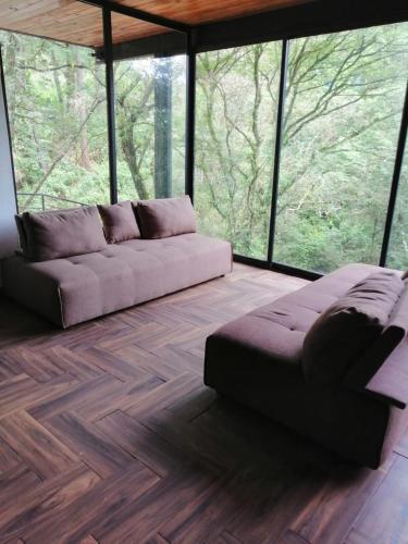 a living room with a couch in front of windows at Mazamitla Pinos del Rio in Mazamitla