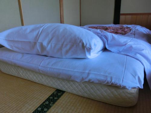 ein unmadenes Bett mit einer blauen Decke drauf in der Unterkunft Tajimaya in Nakatsugawa