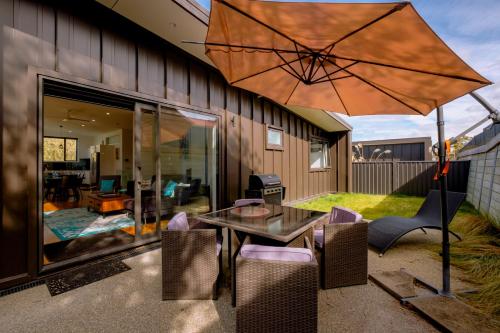 a patio with a table and an umbrella at Kawerau River Retreat - Cromwell Holiday Home in Cromwell