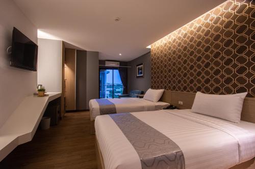 a hotel room with two beds and a television at iChapter Suvarnabhumi in Samutprakarn