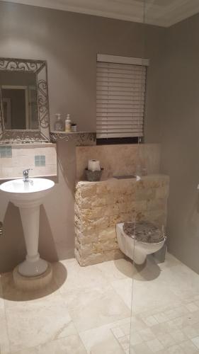 a bathroom with a sink and a toilet and a mirror at The Haven in Jongensfontein