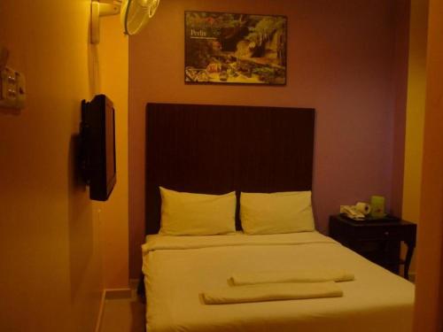 a bedroom with a bed with white sheets and a television at GS Budget Hotel Ampang in Ampang