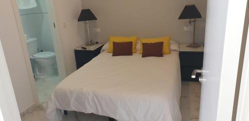 a bed room with a white bedspread and a white toilet at Pensión Barlovento in Málaga