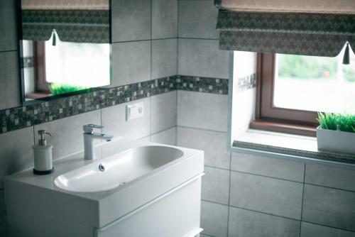 a bathroom with a white sink and two windows at Laurentroom Center in Ukmergė