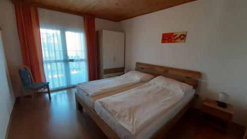 ein Schlafzimmer mit einem Bett, einem Stuhl und einem Fenster in der Unterkunft Ferienwohnungen & Weingut Kroiss Silvia in Illmitz