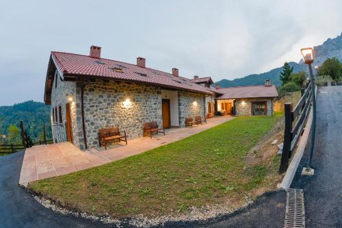 una casa de piedra con un banco a un lado de una carretera en Apartamentos Los Picos de Europa, en Colio