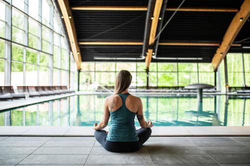 a woman sitting in a yoga pose in front of a pool at Apartments Terme Sveti Martin in Sveti Martin na Muri