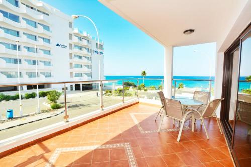 a balcony with a table and chairs and a view of the ocean at Seafront Protaras Villas in Protaras