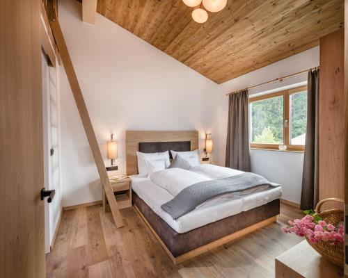 a bedroom with a large bed and a wooden ceiling at Alpwellhotel Burggräfler in Tesimo