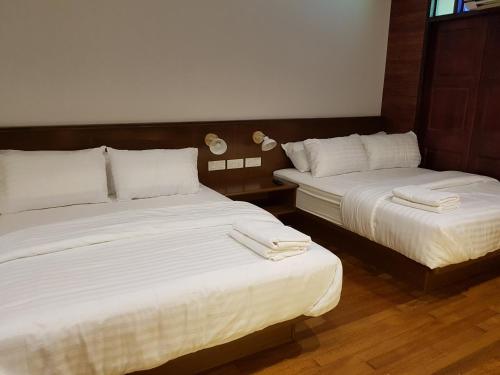 two beds in a hotel room with white sheets at Little Kampung Studio in Teluk Intan
