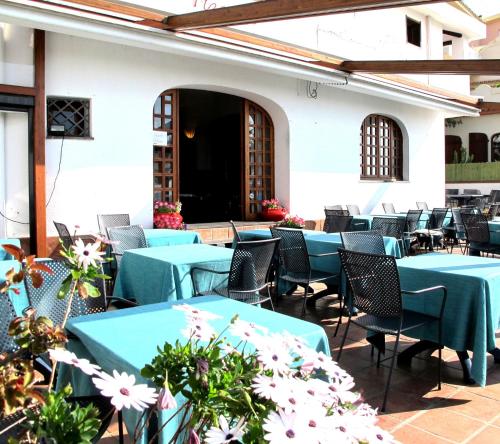 a patio with blue tables and chairs and flowers at Hotel Pop in Cala Gonone