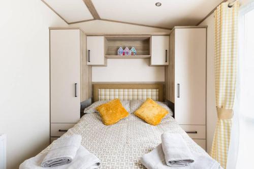 a bedroom with a bed with two yellow pillows at Duckling View in South Cerney