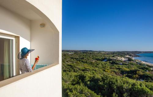 a woman standing on a balcony looking out at the ocean at Ecoresort Le Sirene - Caroli Hotels in Gallipoli