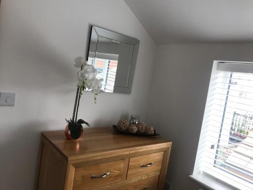 a vase of flowers on top of a dresser with a mirror at No 4 Elizabeth Street in Congleton