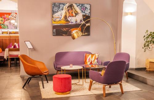a waiting room with purple chairs and a table at Boutique Hotel Dom - Rooms & Suites in Graz