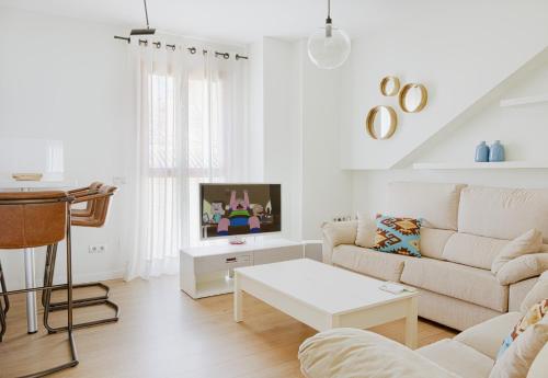 a white living room with a couch and a table at Caleta Homes - Apartamentos Pompidou in Málaga