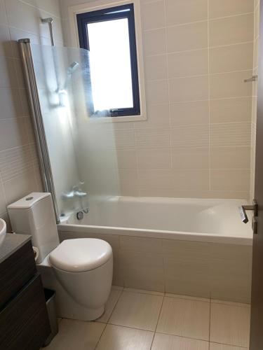 a bathroom with a toilet and a tub and a sink at Artemis Executive Suite in Larnaca