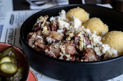 a black bowl of food with meat and biscuits at Hotel Trotuş in Onești