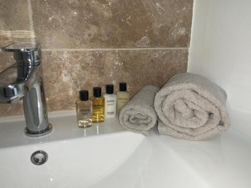 un lavandino in bagno con due asciugamani e bottiglie di sapone di La Chapelle a Mamers
