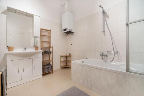 un bagno bianco con vasca e lavandino di Caring Family Apartment Close To The Center a Vienna