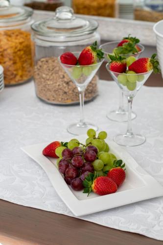 a plate of fruit on a table with wine glasses at Whale Coast Ocean Villa in Hermanus