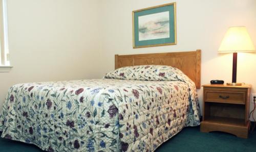 1 dormitorio con 1 cama y 1 mesa con lámpara en Affordable Suites Salisbury, en Salisbury
