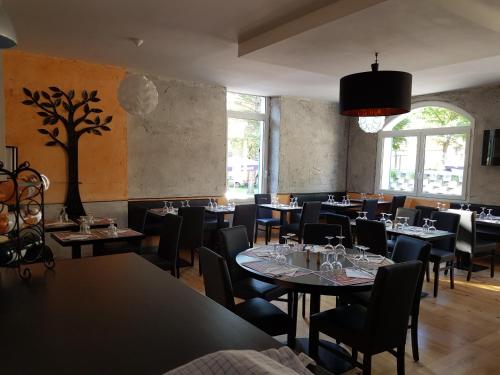 a dining room with tables and chairs and a tree on the wall at alpes hotel barreme in Barrême