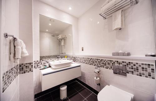 a bathroom with a sink and a toilet and a mirror at Crowne Plaza Leeds, an IHG Hotel in Leeds